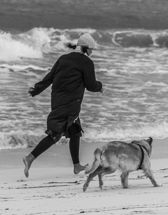 a-person-running-on-a-beach-with-a-dog.jpg a person running on a beach with a dog